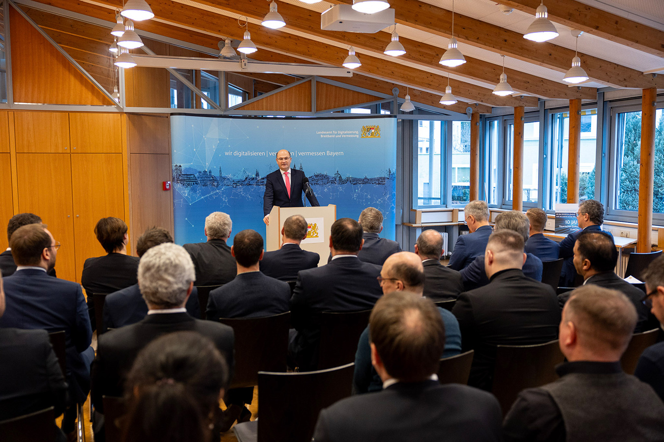 Herren in dunklen Anzügen lauschen der Rede von Staatsminister Albert Füracker, MdL